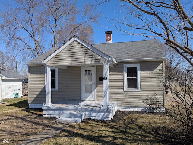 bungalow-style home with a porch, a chimney, and roof with shingles