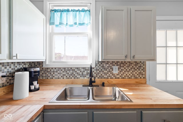 kitchen with tasteful backsplash, butcher block countertops, and a sink