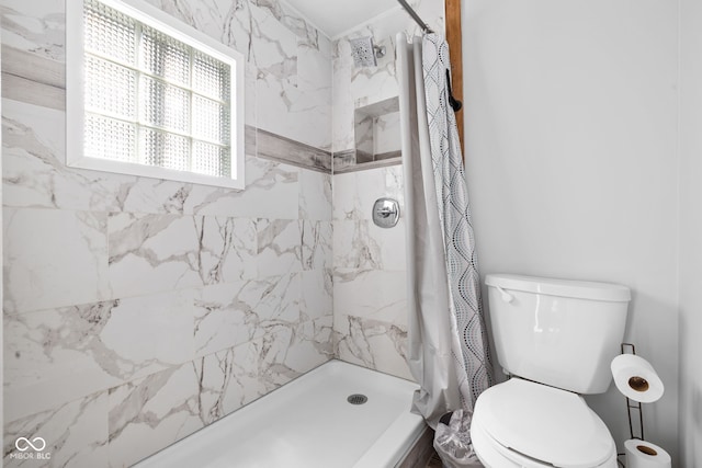 full bath featuring a stall shower and toilet