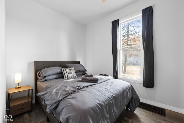 bedroom with wood finished floors, visible vents, and baseboards