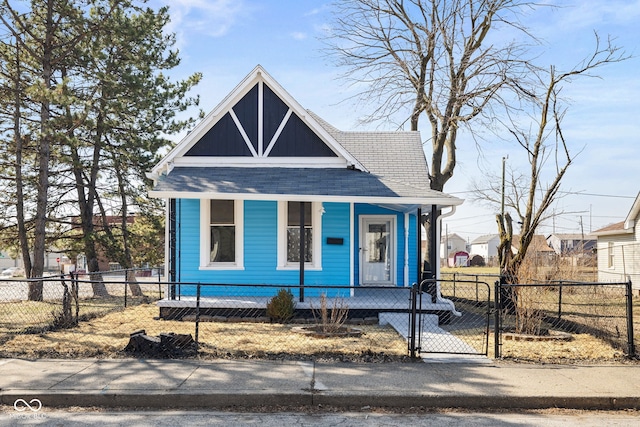 view of front of house featuring a fenced front yard, a porch, a shingled roof, and a gate