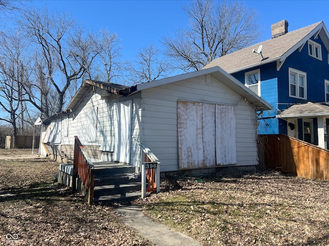 view of property exterior featuring a chimney and fence