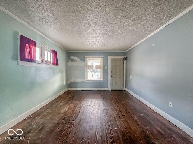 empty room featuring baseboards, a textured ceiling, wood finished floors, and crown molding