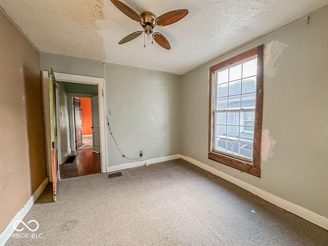 spare room featuring carpet flooring, visible vents, a textured ceiling, and baseboards