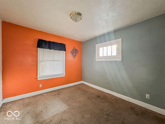 carpeted spare room with baseboards and a textured ceiling