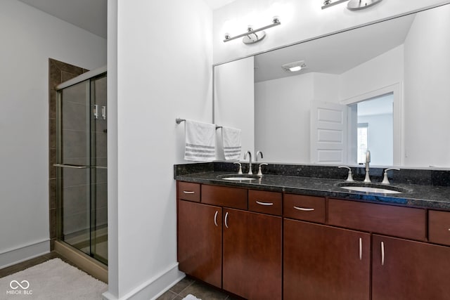 bathroom with a shower stall, double vanity, and a sink