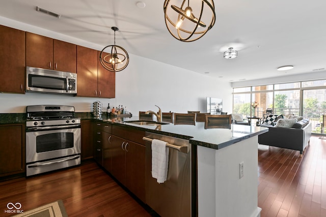 kitchen featuring visible vents, a sink, open floor plan, a peninsula, and appliances with stainless steel finishes