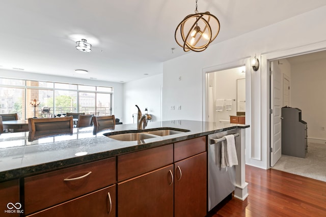 kitchen featuring dark stone countertops, dark wood finished floors, a sink, hanging light fixtures, and stainless steel dishwasher