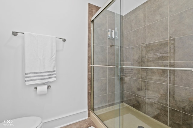 full bathroom with a shower stall, toilet, and tile patterned floors