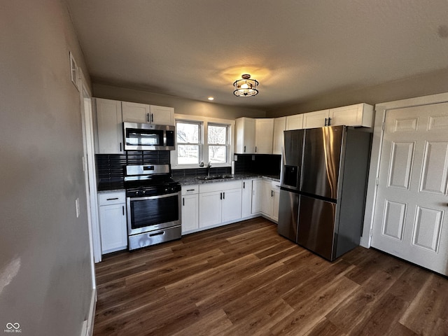 kitchen featuring a sink, stainless steel appliances, dark wood-style flooring, and white cabinetry