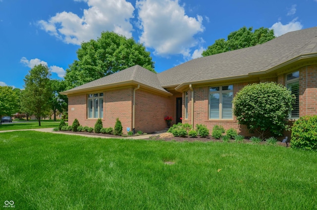 ranch-style house with brick siding, roof with shingles, and a front lawn