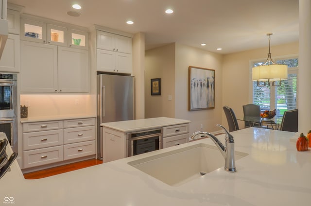 kitchen featuring light countertops, wine cooler, stainless steel appliances, a sink, and pendant lighting