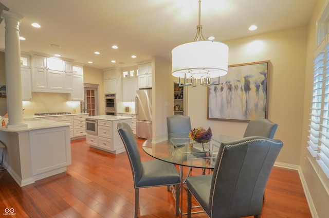 dining space featuring wood finished floors, recessed lighting, and ornate columns