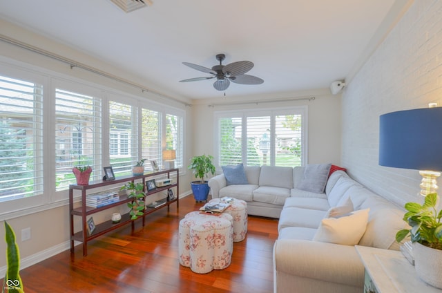 living area with wood finished floors, brick wall, baseboards, visible vents, and ceiling fan