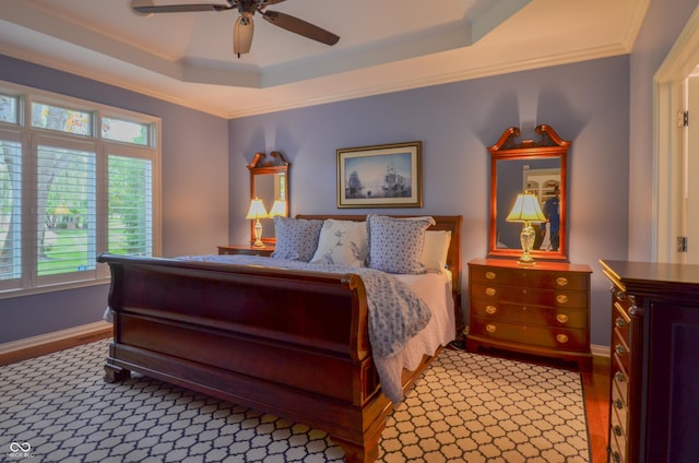 bedroom featuring a ceiling fan, a raised ceiling, crown molding, and baseboards