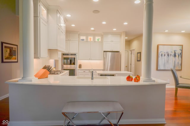 kitchen with dark wood-style floors, a sink, stainless steel appliances, and decorative columns