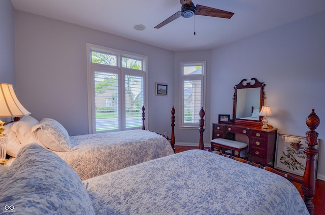 bedroom with baseboards, wood finished floors, multiple windows, and a ceiling fan