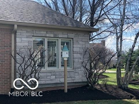 doorway to property with stone siding, brick siding, and a shingled roof