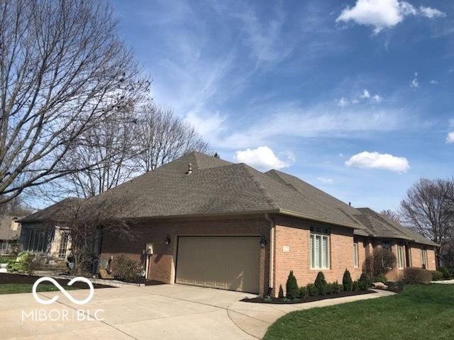 view of home's exterior featuring roof with shingles, concrete driveway, brick siding, a garage, and a yard
