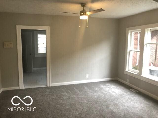 carpeted spare room featuring baseboards, a textured ceiling, and ceiling fan