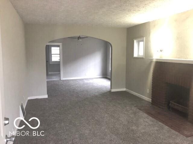 unfurnished room featuring baseboards, arched walkways, and a textured ceiling