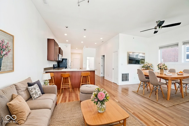 living room with light wood-type flooring, visible vents, ceiling fan, and recessed lighting