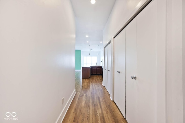 corridor with recessed lighting, light wood-type flooring, and baseboards