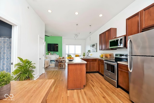 kitchen featuring a peninsula, recessed lighting, light countertops, light wood-style floors, and appliances with stainless steel finishes