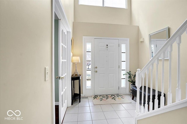 entrance foyer featuring stairway, light tile patterned flooring, and a towering ceiling