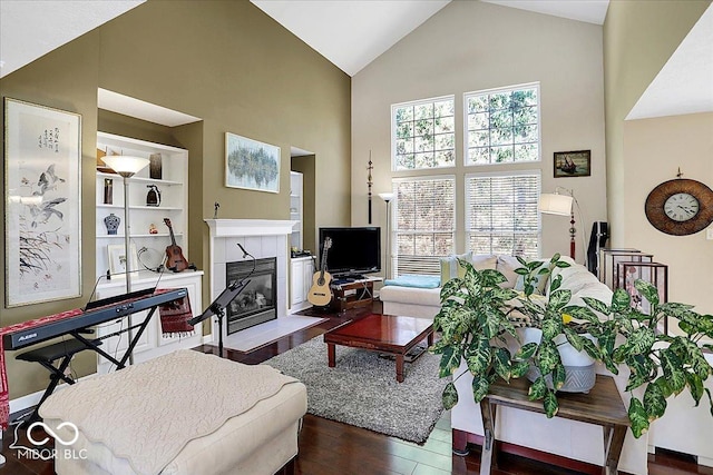 living area with high vaulted ceiling, wood finished floors, and a tiled fireplace