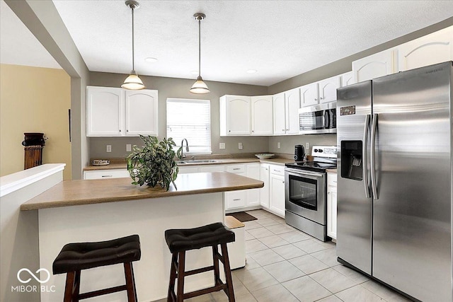 kitchen with a sink, stainless steel appliances, a breakfast bar, and white cabinetry