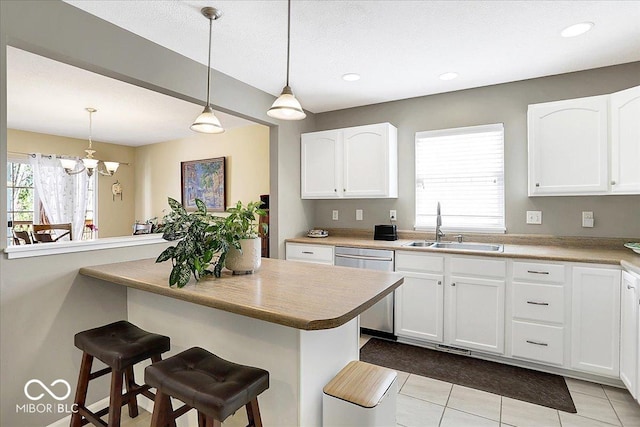 kitchen featuring dishwasher, a breakfast bar, white cabinetry, and a sink