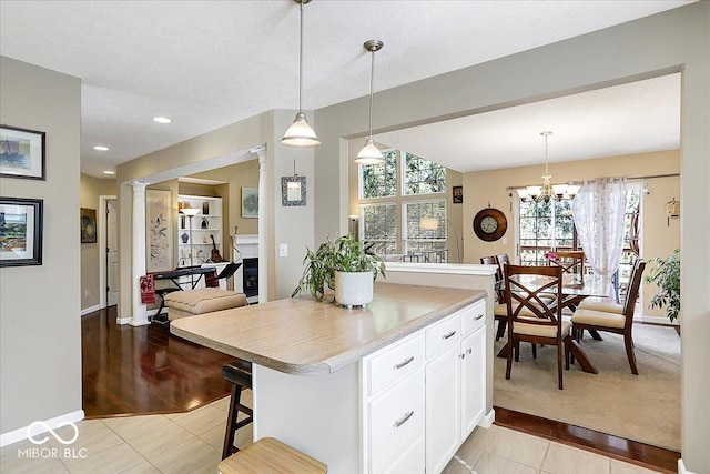 kitchen featuring a textured ceiling, light tile patterned floors, light countertops, pendant lighting, and white cabinetry