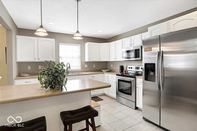 kitchen featuring a sink, a kitchen breakfast bar, white cabinets, and stainless steel appliances