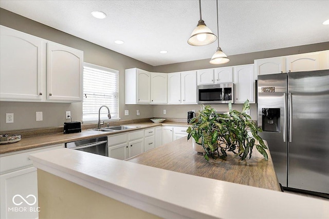 kitchen featuring white cabinetry, pendant lighting, stainless steel appliances, and a sink