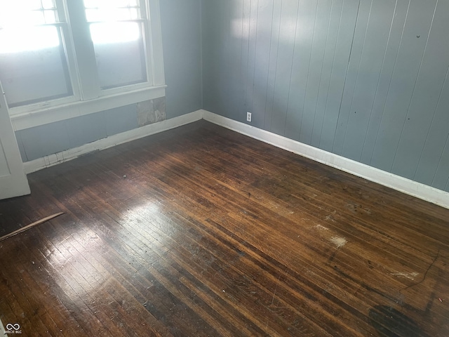 unfurnished room featuring dark wood-type flooring and baseboards