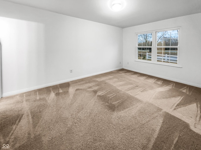 carpeted spare room featuring baseboards