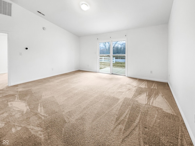 spare room featuring carpet, visible vents, and baseboards