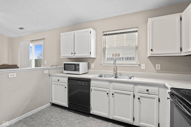 kitchen with visible vents, black appliances, a sink, white cabinets, and light countertops