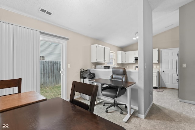 office featuring visible vents, baseboards, a textured ceiling, and vaulted ceiling