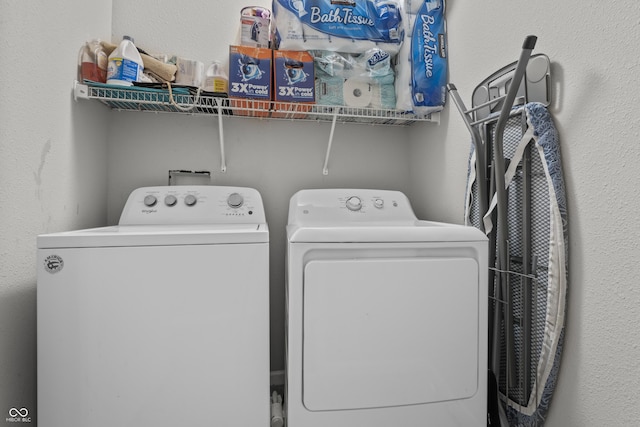 laundry room with laundry area, separate washer and dryer, and a textured wall