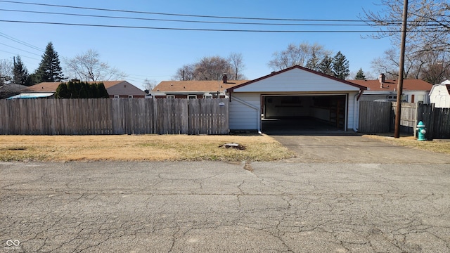 detached garage featuring driveway and fence