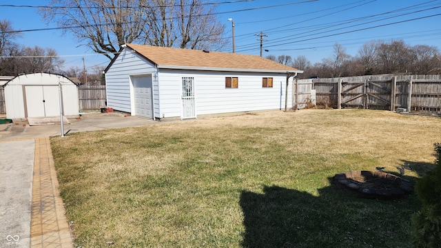 view of yard with a detached garage, an outbuilding, a fenced backyard, and a gate