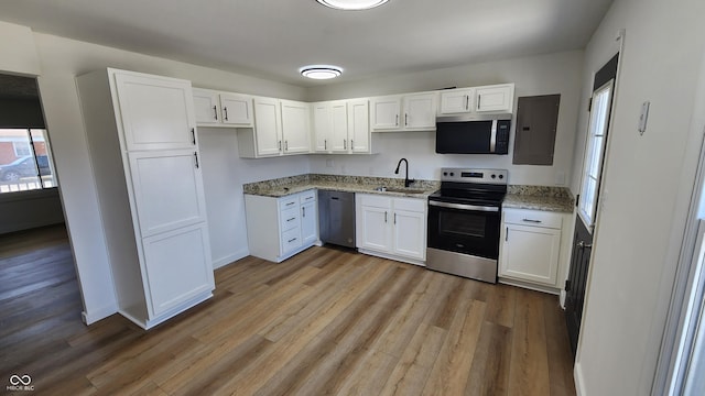 kitchen with light wood-style flooring, a sink, light stone counters, electric panel, and stainless steel appliances