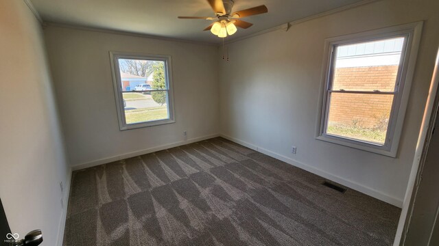 carpeted spare room featuring visible vents, baseboards, ornamental molding, and a ceiling fan