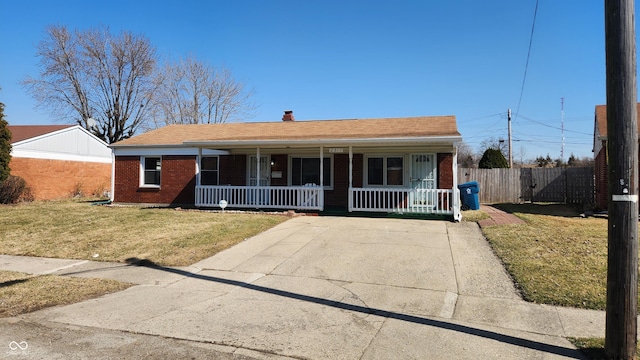 view of front of house featuring brick siding, covered porch, a front lawn, and fence