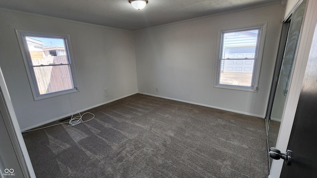 carpeted empty room with a textured ceiling, crown molding, and baseboards