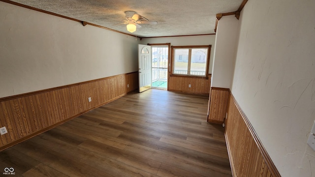 spare room with a wainscoted wall, wood-type flooring, a textured ceiling, and ornamental molding