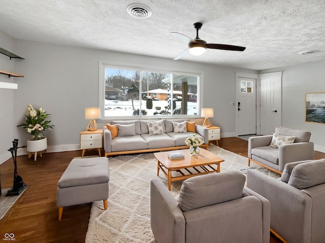 living room featuring a textured ceiling, wood finished floors, visible vents, and baseboards