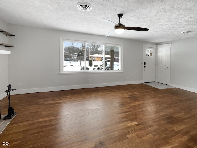 unfurnished living room with visible vents, baseboards, a textured ceiling, and wood finished floors